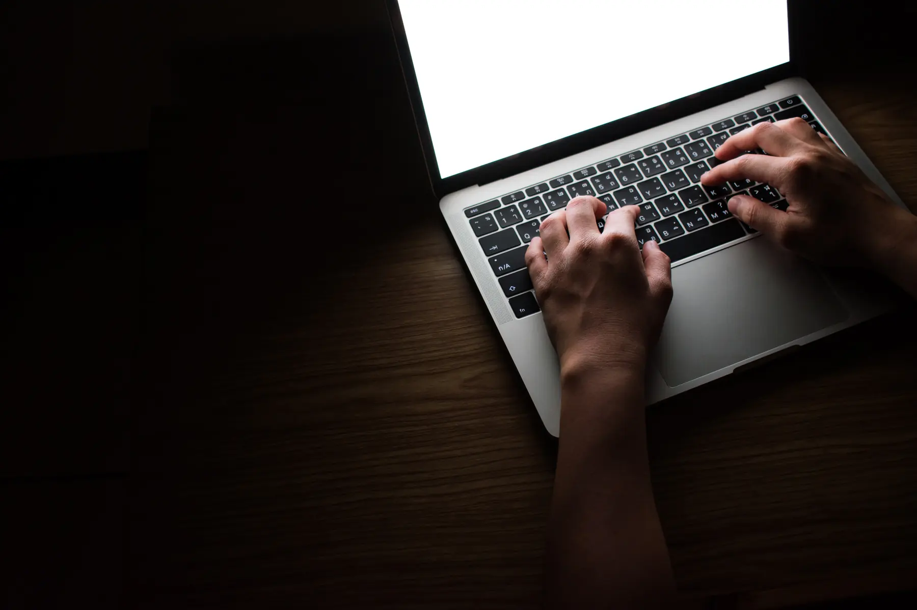 Hands on a laptop keyboard in low light